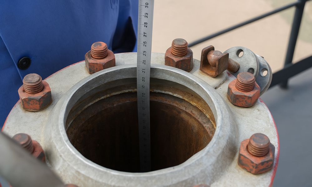 Técnico utilizando régua para medir nível interno de tanque de combustível.